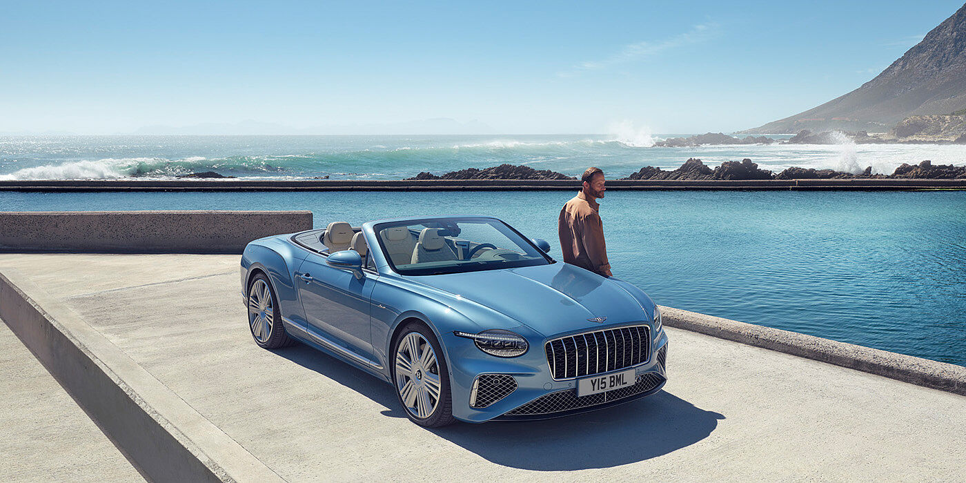 Bentley Beirut New Bentley Continental GTC Azure convertible front view in Light Windsor blue paint with 22 inch ten spoke wheels parked by the sea in the sunshine
