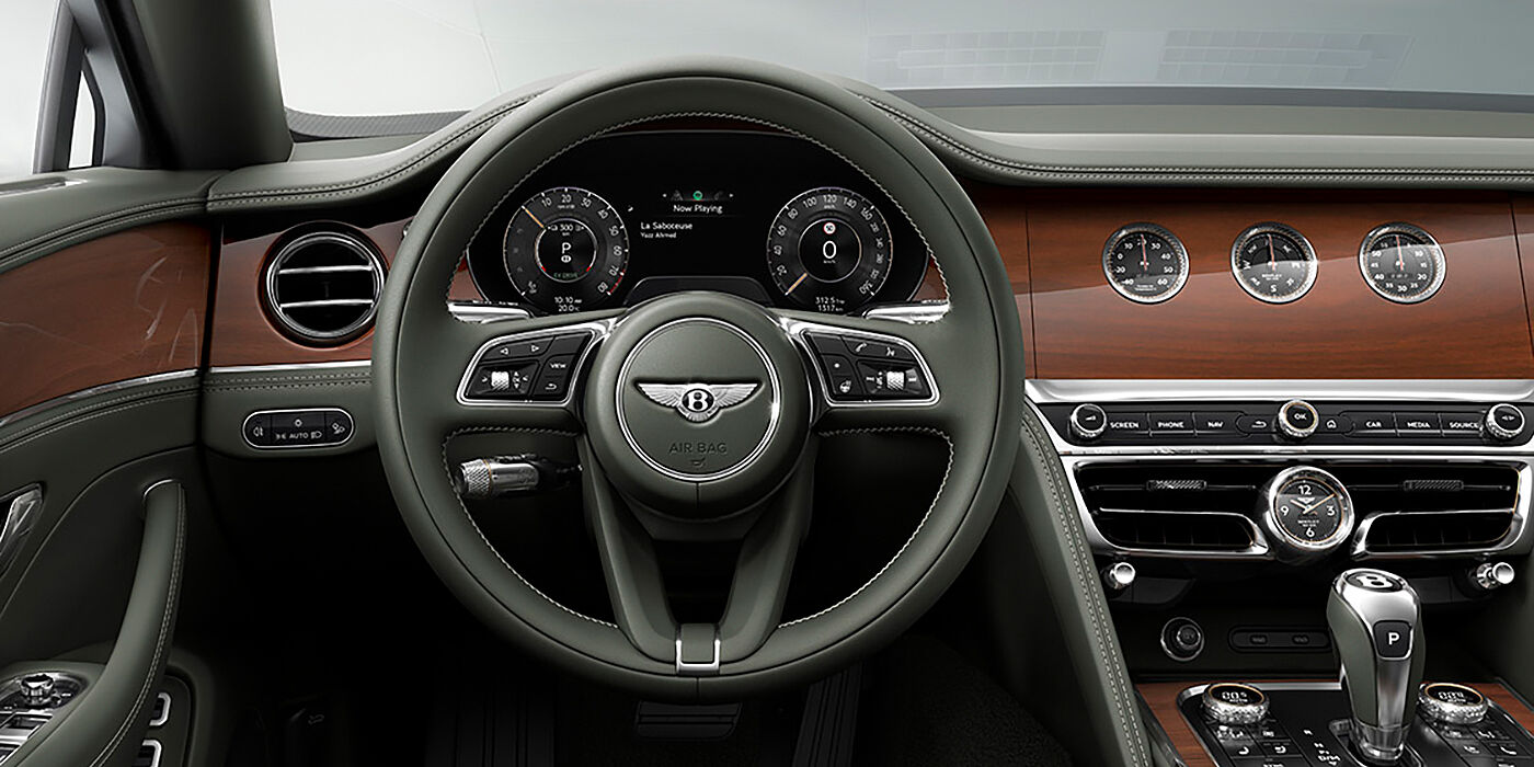 Bentley Beirut New Bentley Flying Spur sedan front cabin in Cumbrian Green hide and Crown Cut walnut veneer showing steering wheel and Rotating Display with three clocks on face