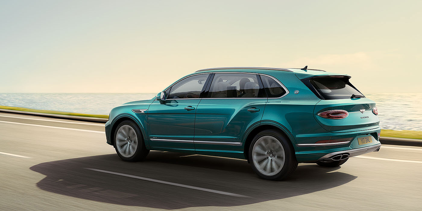 Bentley Beirut Bentley Bentayga Extended Wheelbase Azure luxury SUV rear three quarter in Topaz Blue by Mulliner paint, driving on an ocean road.