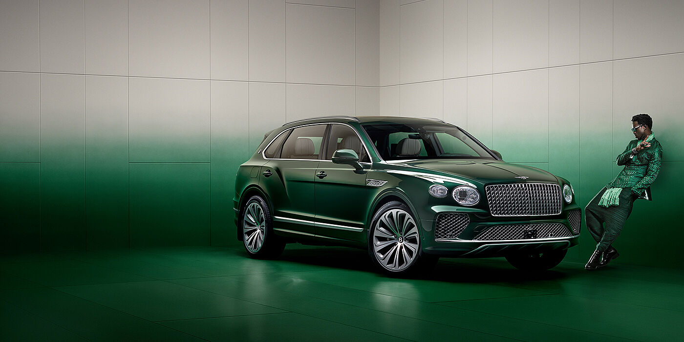 Bentley Beirut Wisdom K leans against wall next to Bentley Bentayga Extended Wheelbase Atelier Edition SUV in Light Emerald green paint