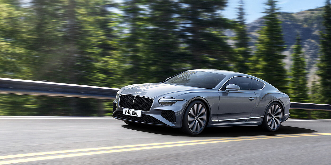 Bentley Beirut New Bentley Continental GT coupe in Silverlake paint and 22 inch ten-spoke wheels, driving dynamically on a tree-lined road in the sunshine