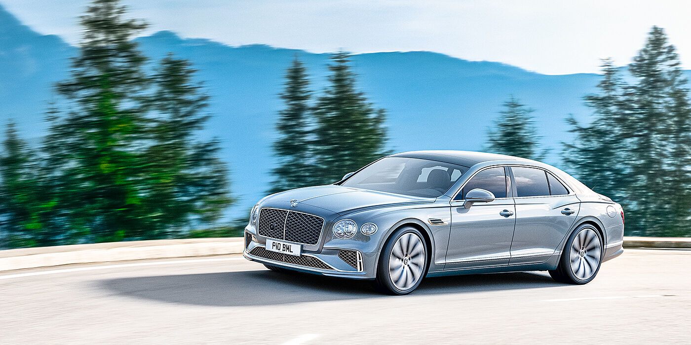 Bentley Beirut New Bentley Flying Spur sedan side view in Silverlake paint with ten spoke wheels and chrome matrix grille driving dynamically on a mountain road