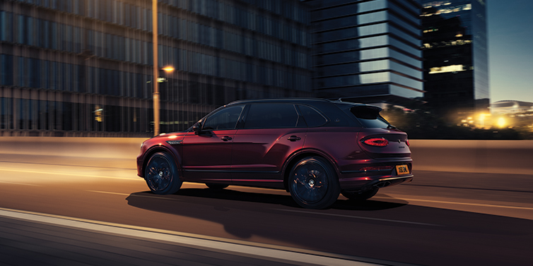 Bentley Beirut Bentley Bentayga Extended Wheelbase Mulliner SUV in Cricket Ball red paint driving dynamically in city at night